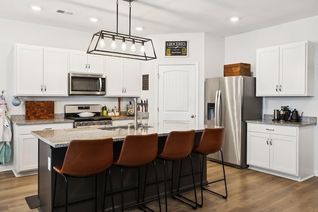 1006 Pepper Stone Dr, Lebanon, TN 37087 - kitchen featuring appliances with stainless steel finishes, dark wood finished floors, white cabinets, an island with sink, and recessed lighting