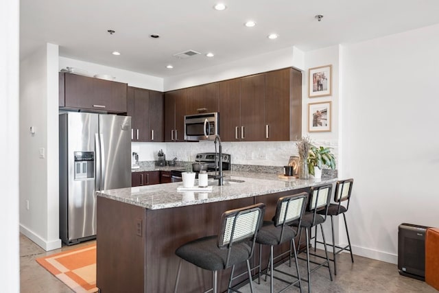 1510 Demonbreun St Unit 701, Nashville, TN 37203 - kitchen featuring appliances with stainless steel finishes, a peninsula, concrete floors, baseboards, and a kitchen breakfast bar