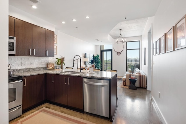 1510 Demonbreun St Unit 701, Nashville, TN 37203 - kitchen featuring stainless steel appliances, a sink, a peninsula, open floor plan, and dark brown cabinets