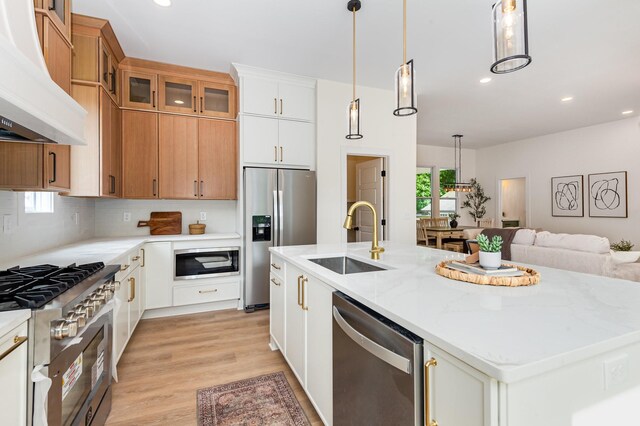311 N 9th St, Nashville, TN 37206 - kitchen featuring premium range hood, a sink, stainless steel appliances, a center island with sink, and light wood-style floors