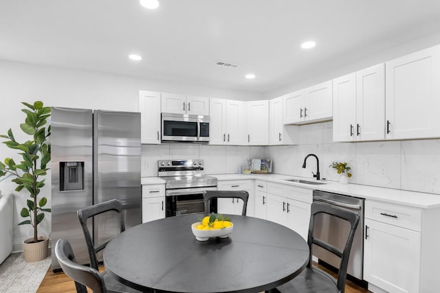 1104 Howell St, Hopkinsville, KY 42240 - kitchen with stainless steel appliances, a sink, light countertops, white cabinets, and decorative backsplash