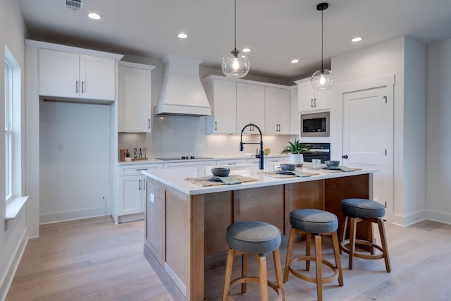 2032 Pleasant Cv, Nashville, TN 37214 - kitchen with custom exhaust hood, stainless steel appliances, light wood-type flooring, white cabinets, and light countertops