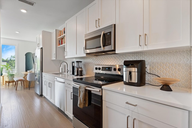 1041 E Trinity Ln Unit 419, Nashville, TN 37216 - kitchen featuring appliances with stainless steel finishes, light countertops, white cabinets, and recessed lighting