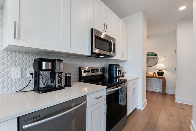 1041 E Trinity Ln Unit 419, Nashville, TN 37216 - kitchen featuring appliances with stainless steel finishes, light wood-style flooring, white cabinetry, decorative backsplash, and light countertops