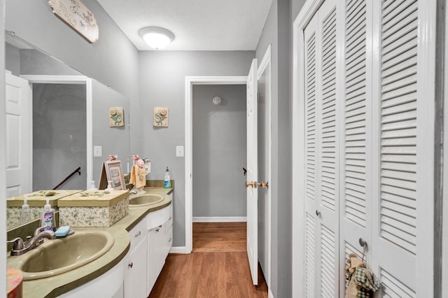 4028 Tomahawk Cir NW, Cleveland, TN 37312 - bathroom featuring a closet, double vanity, wood finished floors, baseboards, and a textured ceiling