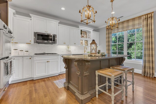 3630 Bear Creek Ln, Thompsons Station, TN 37179 - kitchen with stainless steel microwave, a chandelier, gas cooktop, white cabinetry, and crown molding