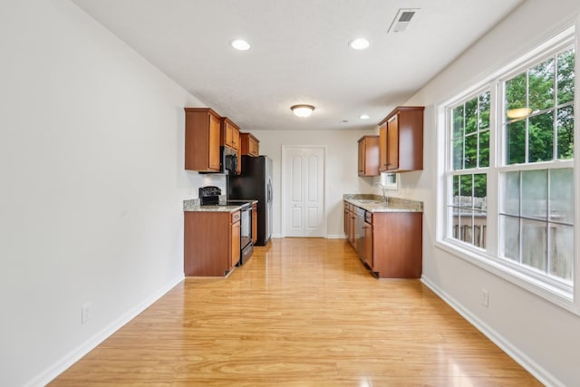 2889 Sharpie Dr, Clarksville, TN 37040 - kitchen with stainless steel appliances, brown cabinetry, light wood-style floors, baseboards, and recessed lighting