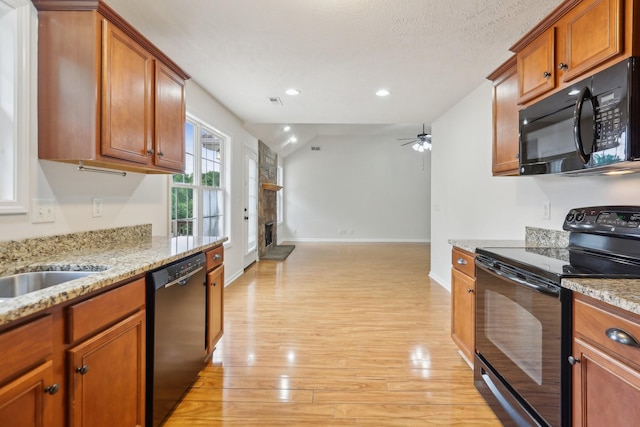 2889 Sharpie Dr, Clarksville, TN 37040 - kitchen featuring black appliances, light wood-type flooring, a ceiling fan, baseboards, and a stone fireplace