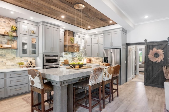 2878 Fly Rd, Santa Fe, TN 38482 - kitchen with gray cabinetry, appliances with stainless steel finishes, a kitchen bar, light wood finished floors, and light stone countertops