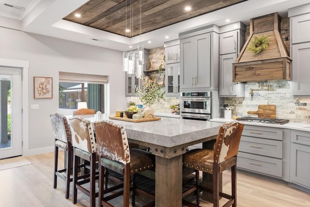 2878 Fly Rd, Santa Fe, TN 38482 - kitchen with gray cabinets, premium range hood, light wood-style floors, a raised ceiling, and decorative backsplash
