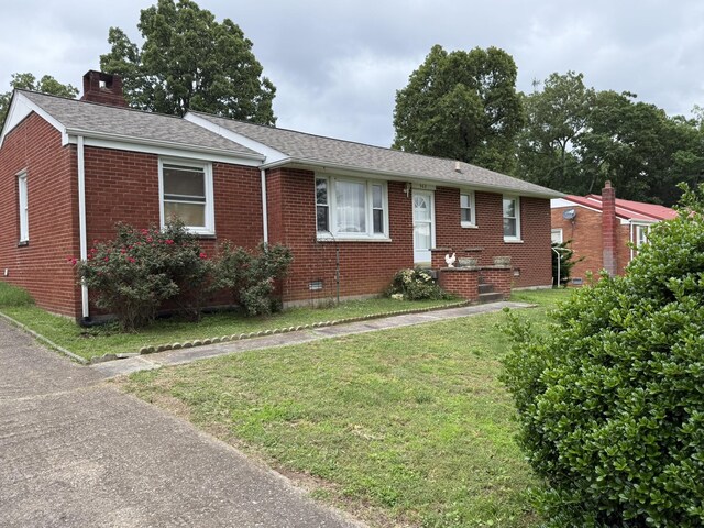 563 Ashe Ave, New Johnsonville, TN 37134 - view of front of house featuring brick siding, a chimney, a front lawn, and roof with shingles