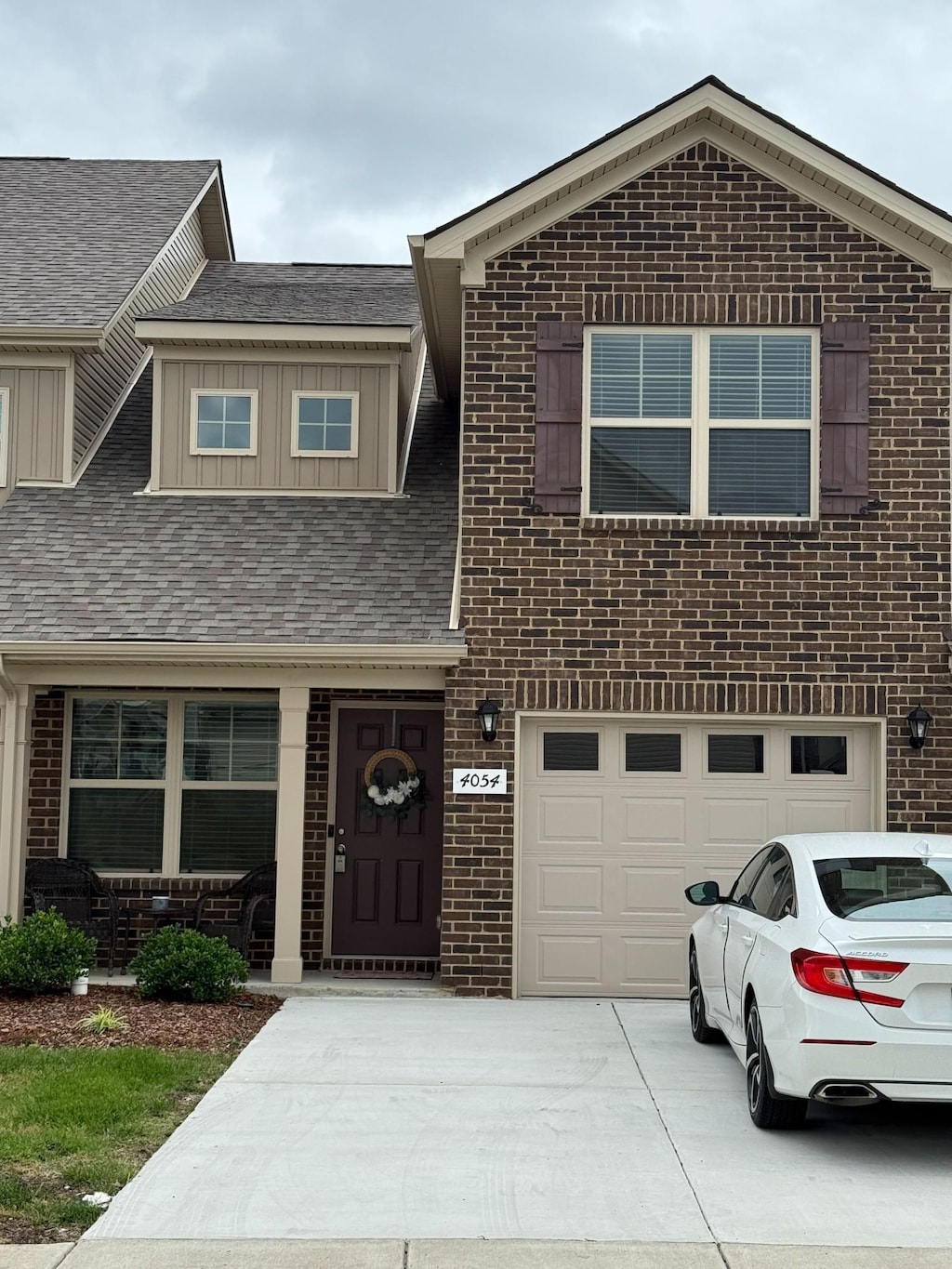 4054 Utica St, Smyrna, TN 37167 - view of front of property featuring brick siding, a garage, driveway, a shingled roof, and board and batten siding