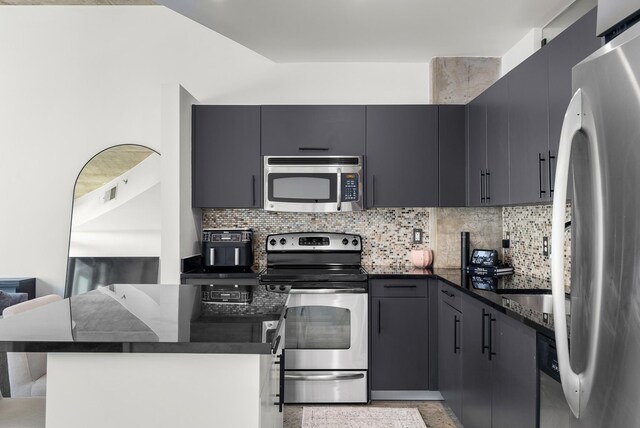 600 12th Ave S Unit 1208, Nashville, TN 37203 - kitchen featuring appliances with stainless steel finishes, decorative backsplash, dark stone counters, and open floor plan