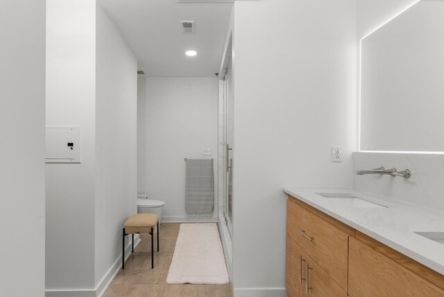 600 12th Ave S Unit 1208, Nashville, TN 37203 - bathroom with toilet, a stall shower, baseboards, double vanity, and recessed lighting
