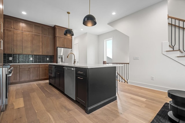 6104 Cowden Ave Unit A, Nashville, TN 37209 - kitchen with appliances with stainless steel finishes, light wood-style flooring, light countertops, backsplash, and hanging light fixtures