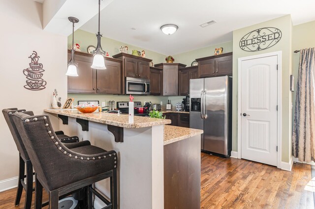 1026 Grace Meade, Ashland City, TN 37015 - kitchen with stainless steel appliances, dark brown cabinetry, a peninsula, a kitchen bar, and wood finished floors