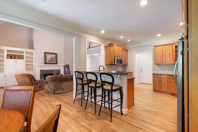 205 Saint Anne Way, Franklin, TN 37064 - kitchen with appliances with stainless steel finishes, ornamental molding, a breakfast bar area, recessed lighting, and light wood-style flooring