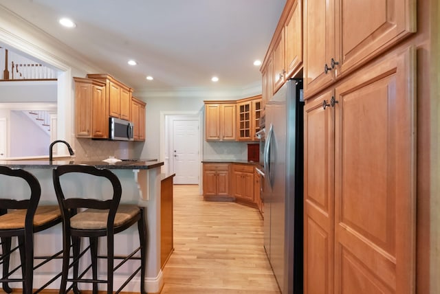 205 Saint Anne Way, Franklin, TN 37064 - kitchen with appliances with stainless steel finishes, a breakfast bar area, crown molding, a peninsula, and light wood-style flooring