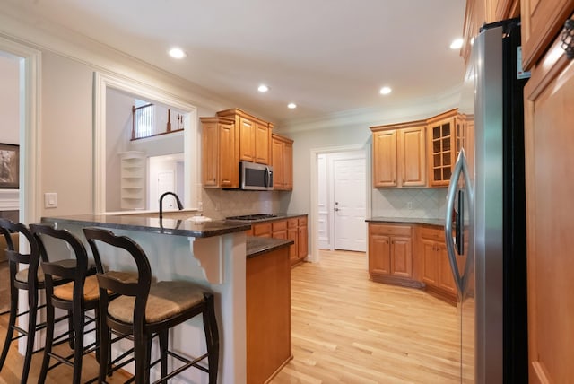 205 Saint Anne Way, Franklin, TN 37064 - kitchen featuring appliances with stainless steel finishes, crown molding, a kitchen bar, tasteful backsplash, and light wood-style floors