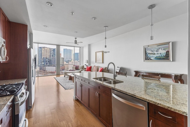 900 20th Ave S Unit 909, Nashville, TN 37212 - kitchen featuring appliances with stainless steel finishes, a sink, light wood finished floors, open floor plan, and decorative light fixtures
