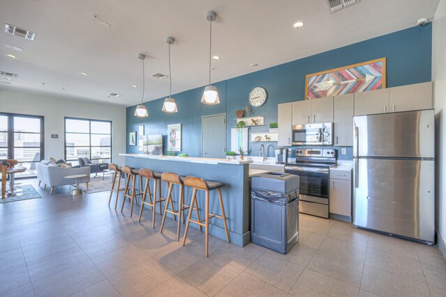 1900 12th Ave S Unit 406, Nashville, TN 37203 - kitchen with stainless steel appliances, a kitchen bar, light countertops, a sink, and hanging light fixtures