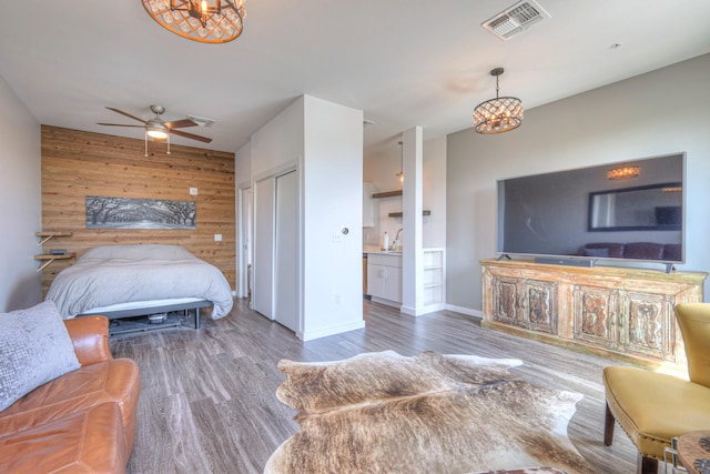 1900 12th Ave S Unit 406, Nashville, TN 37203 - bedroom featuring a chandelier, wooden walls, an accent wall, wood finished floors, and connected bathroom