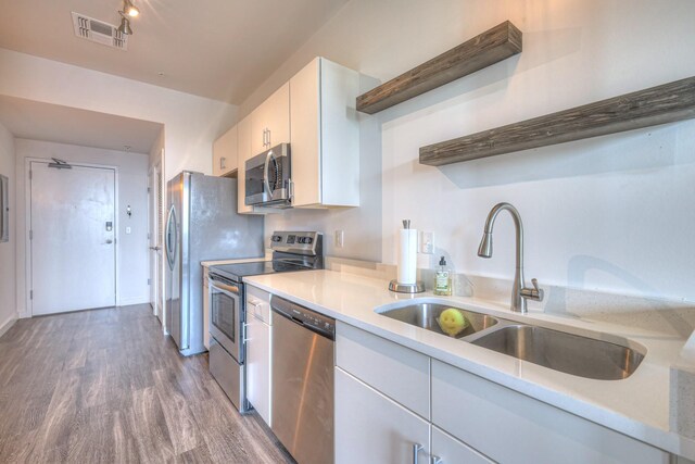 1900 12th Ave S Unit 406, Nashville, TN 37203 - kitchen with appliances with stainless steel finishes, a sink, white cabinetry, wood finished floors, and light countertops