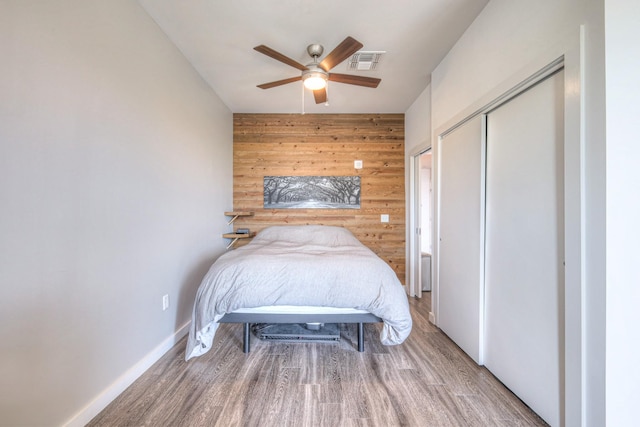 1900 12th Ave S Unit 406, Nashville, TN 37203 - bedroom with wooden walls, a closet, wood finished floors, a ceiling fan, and baseboards