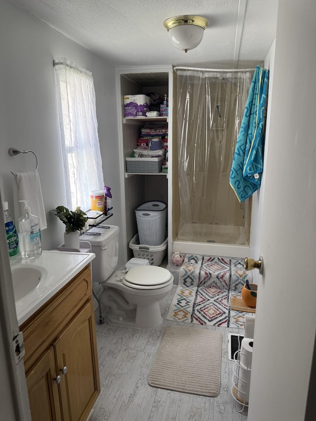 329 Queen Ave, Nashville, TN 37207 - bathroom with toilet, vanity, a stall shower, wood finished floors, and a textured ceiling