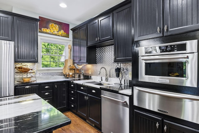 314 W 6th St Unit 7, Columbia, TN 38401 - kitchen featuring a warming drawer, stainless steel appliances, a sink, dark cabinetry, and decorative backsplash