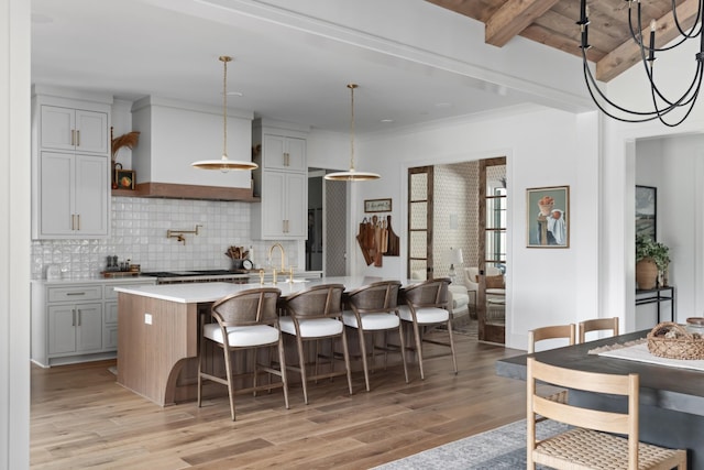 1936 Silver Fox Rd, Thompsons Station, TN 37179 - kitchen with light wood-style flooring, tasteful backsplash, light countertops, a breakfast bar, and an island with sink
