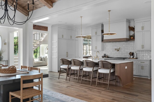 1936 Silver Fox Rd, Thompsons Station, TN 37179 - kitchen featuring wood finished floors, an island with sink, tasteful backsplash, custom range hood, and plenty of natural light