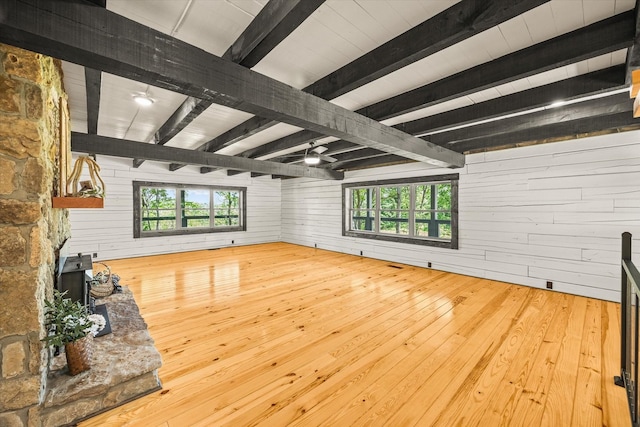 4221 New Hope Rd, Celina, TN 38551 - unfurnished living room with wooden walls, beamed ceiling, wood-type flooring, and a wood stove