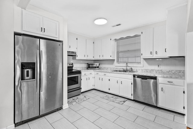 109 Garwood Dr, Nashville, TN 37210 - kitchen featuring stainless steel appliances, a sink, under cabinet range hood, white cabinets, and light stone countertops