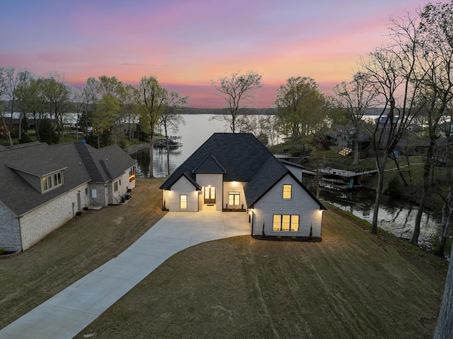 199 Beach Rd N, Killen, AL 35645 - back of house at dusk with a water view, concrete driveway, roof with shingles, and a yard
