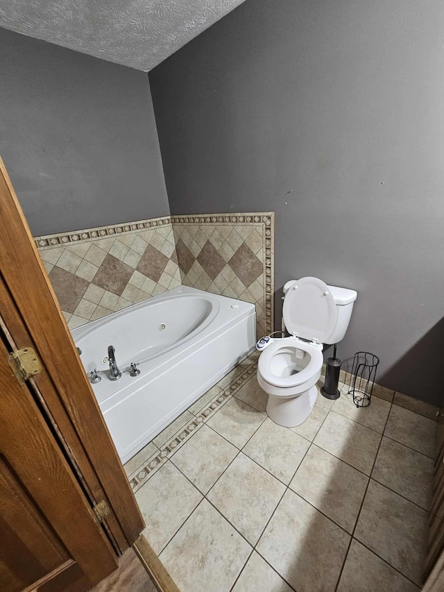 102 Hazelnut Ave, Camden, TN 38320 - bathroom featuring a jetted tub, toilet, tile patterned floors, and a textured ceiling