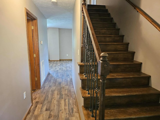 102 Hazelnut Ave, Camden, TN 38320 - stairway featuring wood finished floors, a textured ceiling, and baseboards