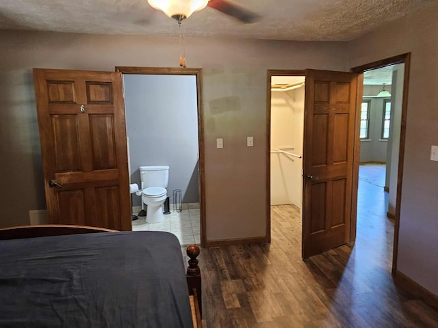102 Hazelnut Ave, Camden, TN 38320 - bedroom featuring wood finished floors, a walk in closet, baseboards, a textured ceiling, and ensuite bath