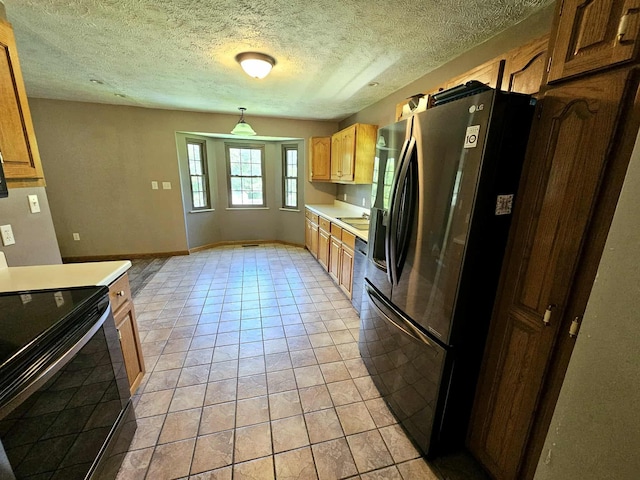 102 Hazelnut Ave, Camden, TN 38320 - kitchen with black range with electric stovetop, stainless steel fridge, light countertops, a textured ceiling, and light tile patterned flooring