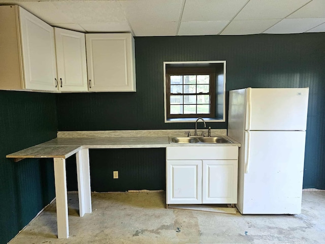 102 Hazelnut Ave, Camden, TN 38320 - kitchen with freestanding refrigerator, a sink, a paneled ceiling, white cabinets, and concrete flooring