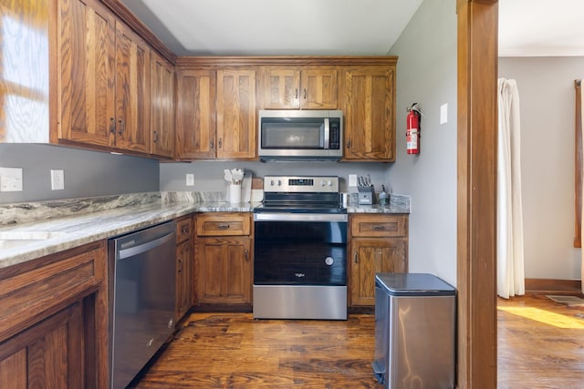 2890 Ellis Ln, Palmyra, TN 37142 - kitchen with appliances with stainless steel finishes, brown cabinets, dark wood finished floors, and light stone counters