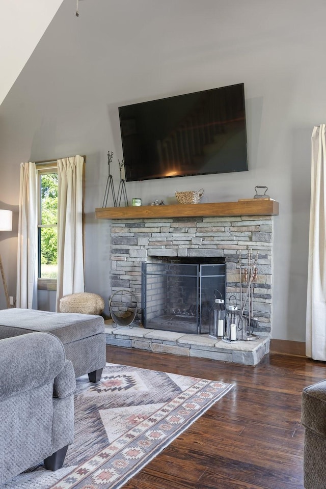 2890 Ellis Ln, Palmyra, TN 37142 - living area featuring a stone fireplace, wood finished floors, vaulted ceiling, and baseboards