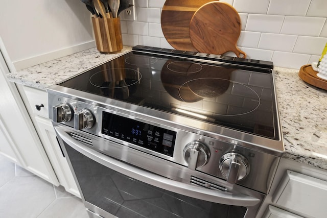 519 Glen Echo Dr, Old Hickory, TN 37138 - kitchen view of stainless steel electric range, backsplash, light stone countertops, and white cabinetry