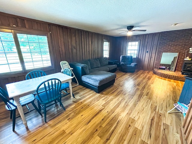 126 Carroll St S, Bruceton, TN 38317 - living area featuring a textured ceiling, light wood-type flooring, a ceiling fan, and wooden walls