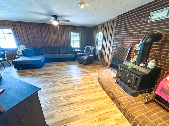 126 Carroll St S, Bruceton, TN 38317 - living room with a wood stove, wood finished floors, a textured ceiling, a ceiling fan, and wood walls