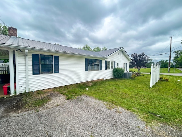 126 Carroll St S, Bruceton, TN 38317 - view of property exterior with central air condition unit, a yard, and metal roof