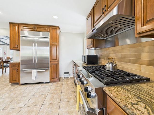 695 Bayshore Dr, Cadiz, KY 42211 - kitchen featuring stainless steel appliances, under cabinet range hood, light stone counters, decorative backsplash, and brown cabinetry
