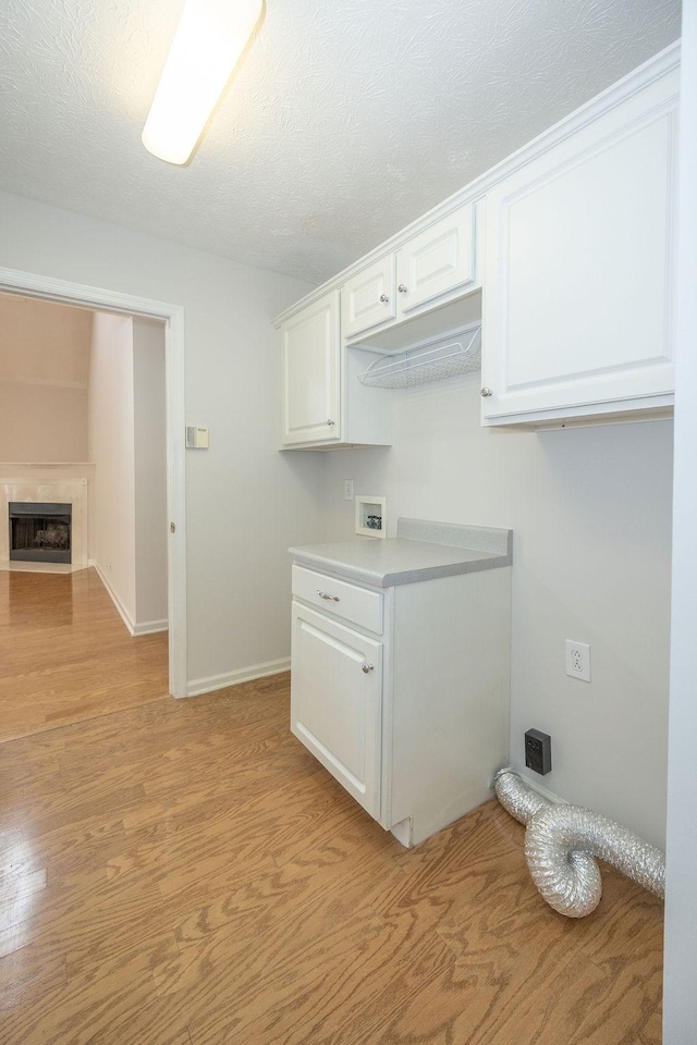 2818 Crazy Horse, Murfreesboro, TN 37127 - laundry area with baseboards, cabinet space, washer hookup, a fireplace with flush hearth, and light wood-style floors
