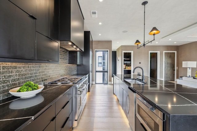 1016B 9th Ave S, Nashville, TN 37203 - kitchen featuring stainless steel appliances, dark cabinets, wall chimney range hood, backsplash, and a sink