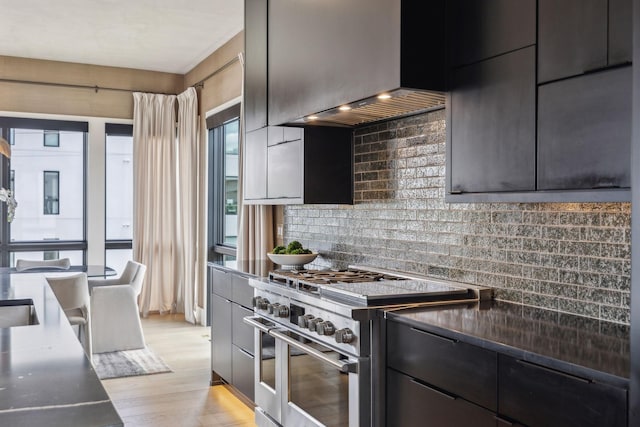 1016B 9th Ave S, Nashville, TN 37203 - kitchen with range with two ovens, backsplash, light wood-style floors, wall chimney range hood, and dark countertops